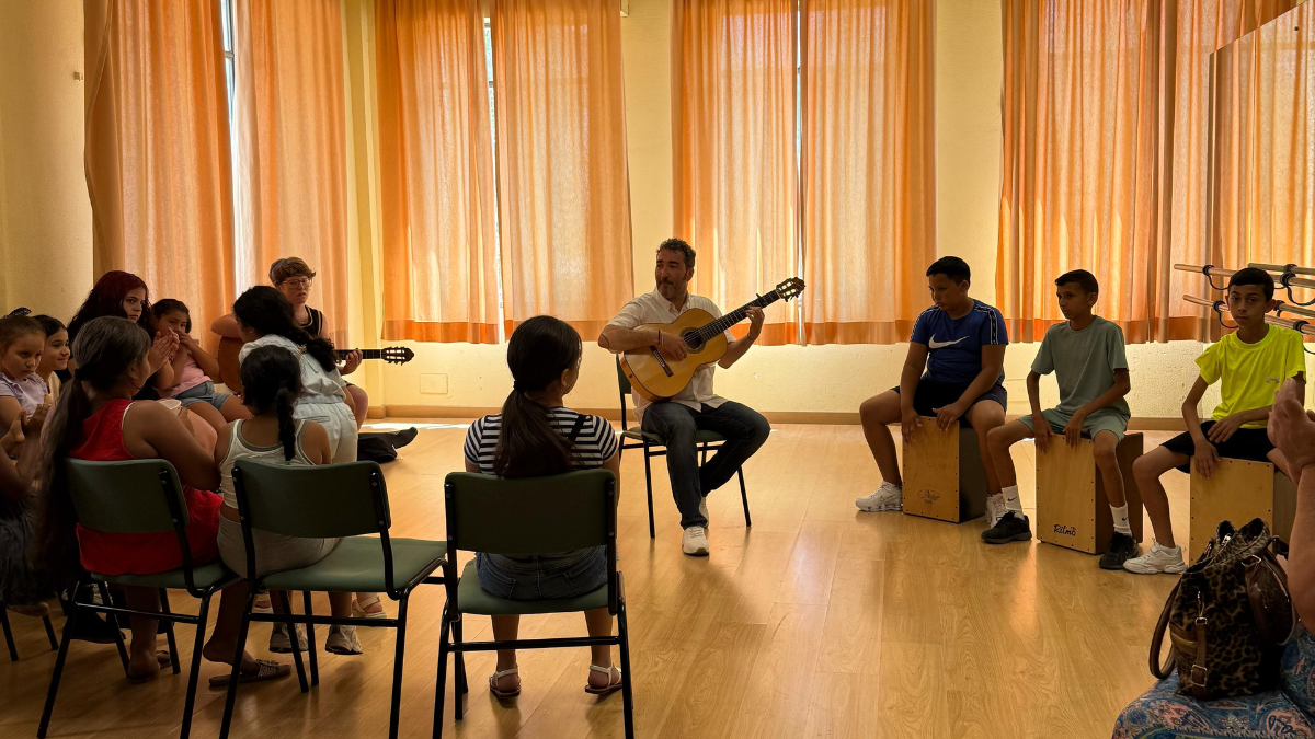 Guitarrista enseñando a niños en el proyecto Un Niño una Guitarra